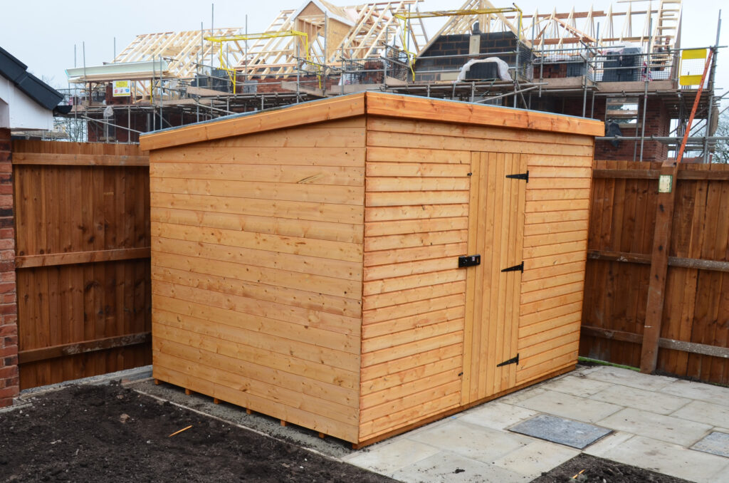 Newly installed Secured By Design Wooden bike Shed, complete with timber clad, hasp and staple, padlock and ground anchors. Located outdoors, in a newly constructed housing estate.