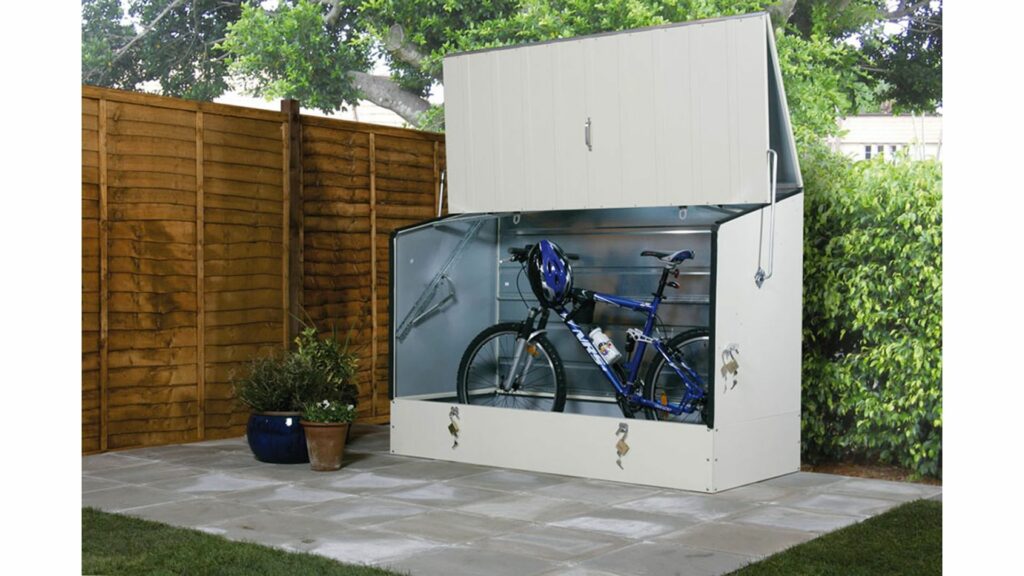 The Bike Protection Box is located outdoors in the back garden with the doors wide open, showing the vast space available for storing essential items such as your bike and cycling equipment. Showcasing the benefits of bike storage for the garden. 
