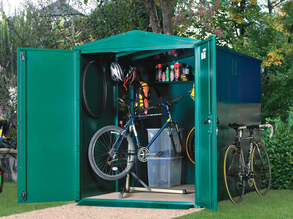 The Secured By Design Metal Bike Shed is located outdoors in the garden with the doors wide open, showing the vast space available for storing essential items such as your bike and cycling equipment.