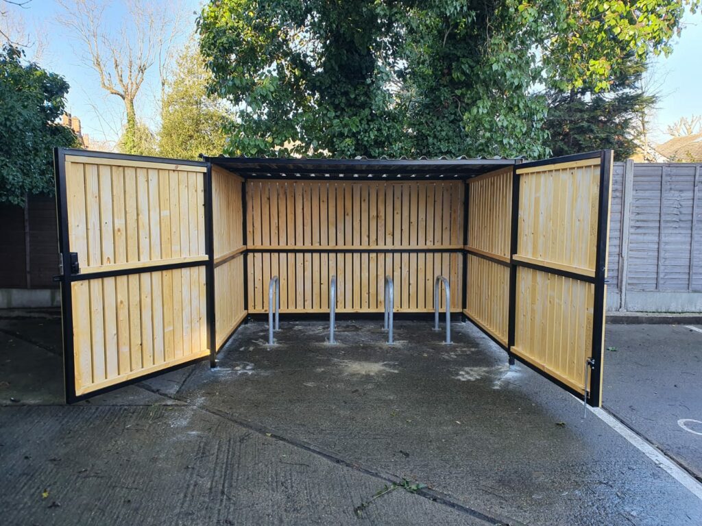 Secure Cycle Store's newly installed timber clad bike shelter, with timber clad swing gates and digital combination lock. This shelter is outdoors and is housing 4 Sheffield bike stands.