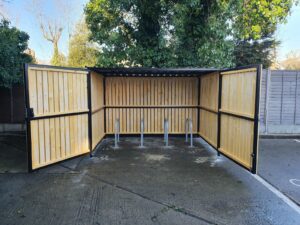 Secure Cycle Store's newly installed timber clad bike shelter, with timber clad swing gates and digital combination lock. This shelter is outdoors and is housing 4 Sheffield bike stands.