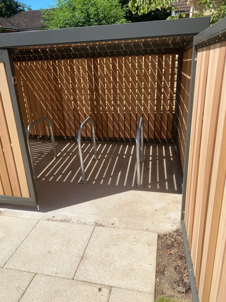 Secure Cycle Store's bespoke low level timber clad bike shelter, doors open showcasing Sheffield Bike Stands. installed for residential use in Scholar's Green, Cheshire. 