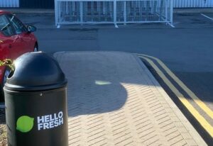 newly installed merton mesh bike shelter, located outdoors behind hello fresh bin.