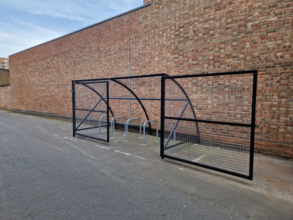 10 space Canal Curved Cycle Storage Shelter installation. A secure gated design, galvanised steel frame. A durable solution for secure cycle storage across commercial, workplace and public locations. 