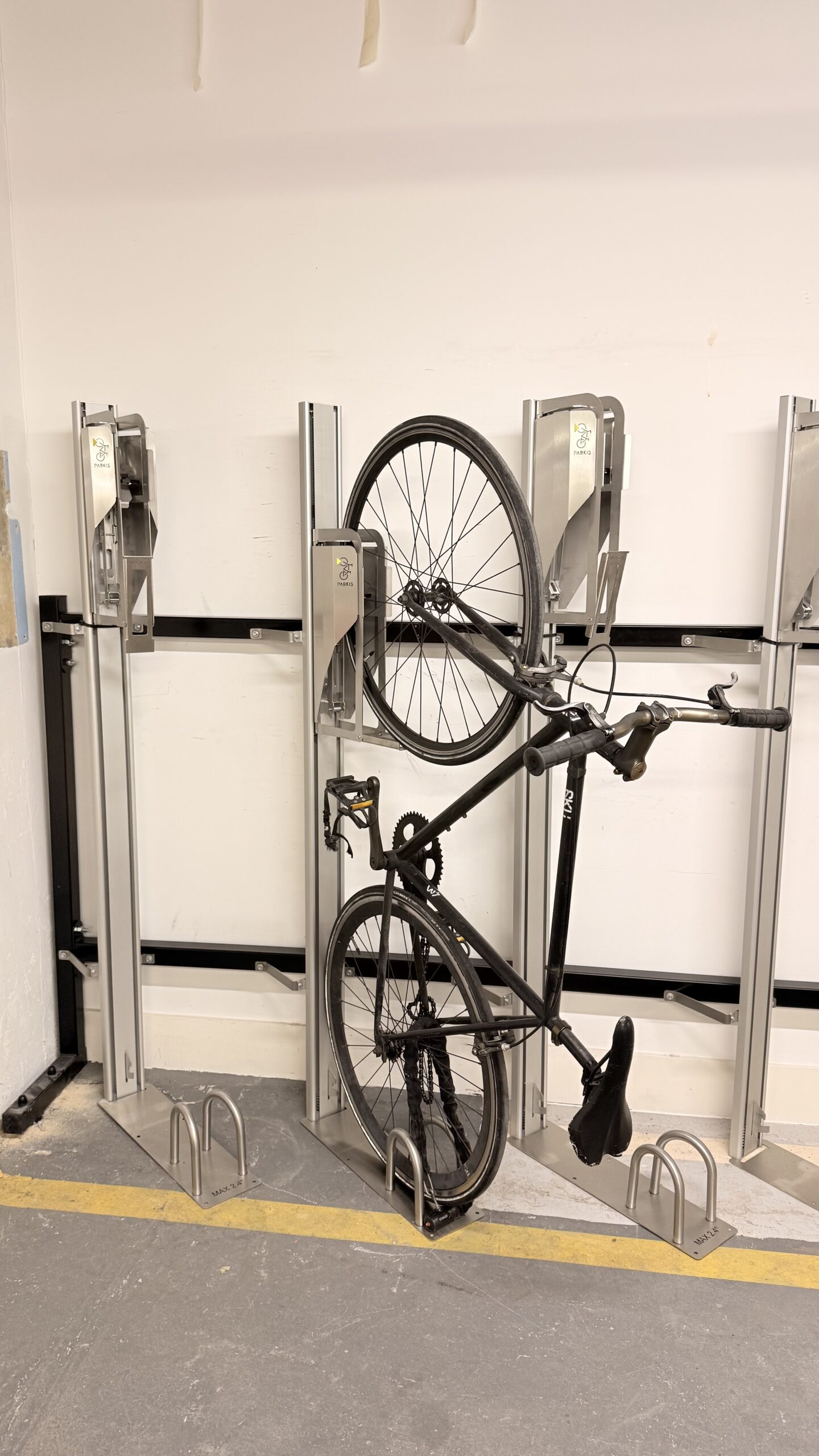Bike in a vertical locked position to save space and efficiently store bikes in a storage and security solution. Located in a commercial building with high footfall.