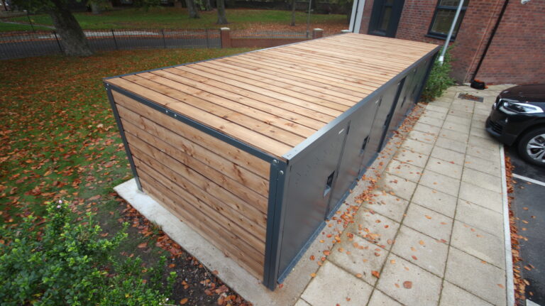 The facade houses Six Two-Bike Lockers In Anthracite Grey, providing ample storage space for residents to store their bikes, equipment, and accessories.
